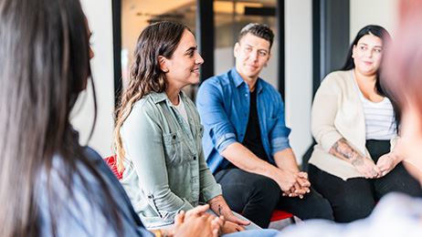 Three women and one man sitting in a circle on chairs for group therapy